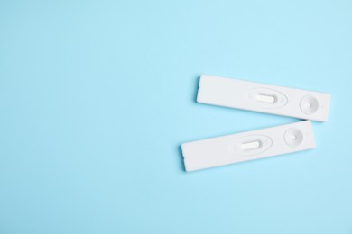 Photo of Two disposable express hepatitis tests on light blue background, flat lay. Space for text