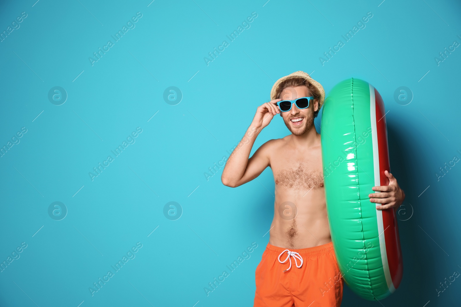 Photo of Young man in shorts with inflatable ring against color background. Space for text