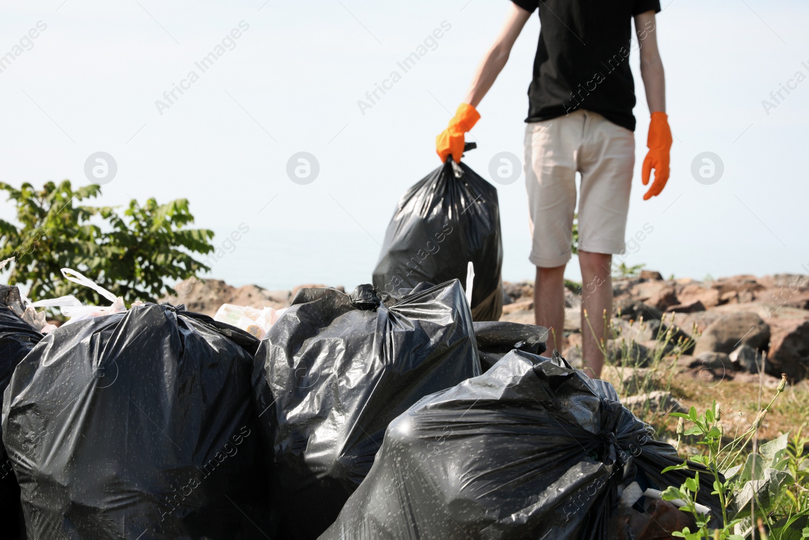 Photo of Man with trash bag full of garbage in nature, closeup. Environmental Pollution concept