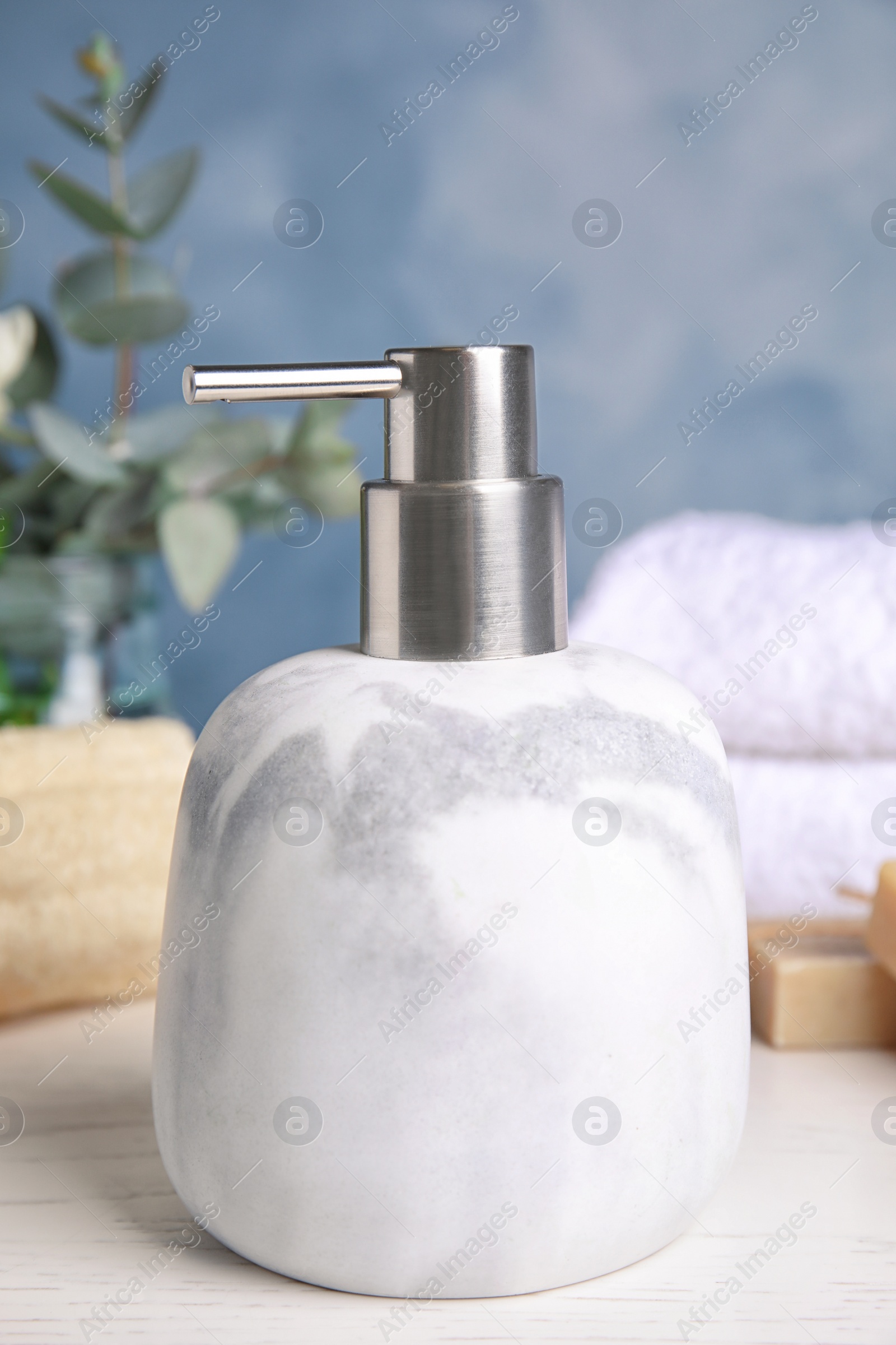 Photo of Modern marble soap dispenser on light table