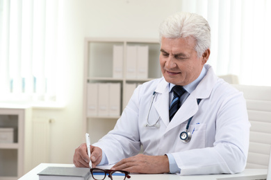 Senior doctor working at table in office