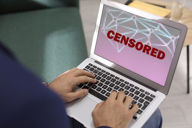 Display with censorship sign. Man using laptop indoors, closeup
