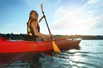 Happy woman in life jacket kayaking on river. Summer activity