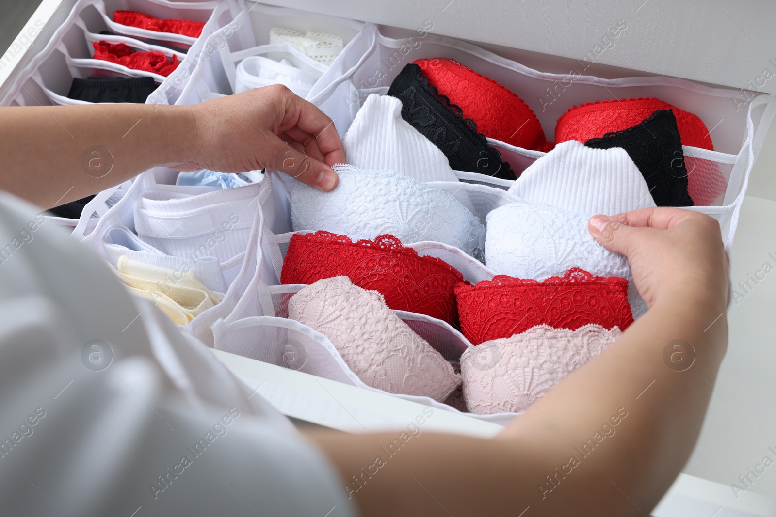 Photo of Woman putting underwear into organizer in drawer, closeup