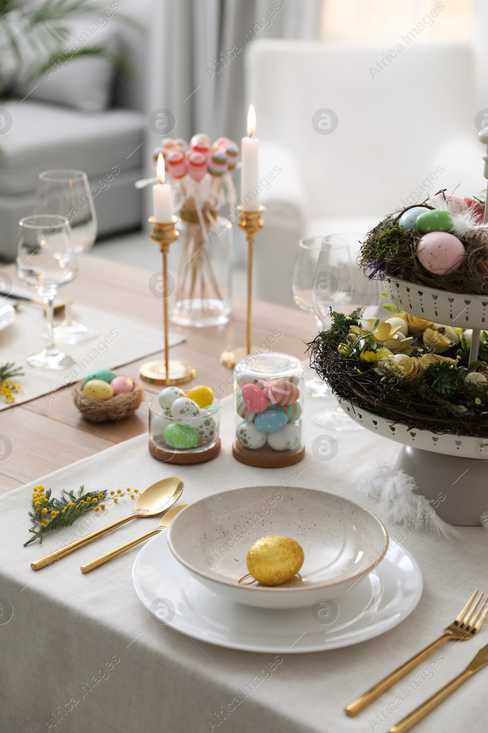 Photo of Beautiful Easter table setting with burning candles and floral decor indoors