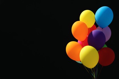 Photo of Bunch of colorful balloons on black background. Space for text