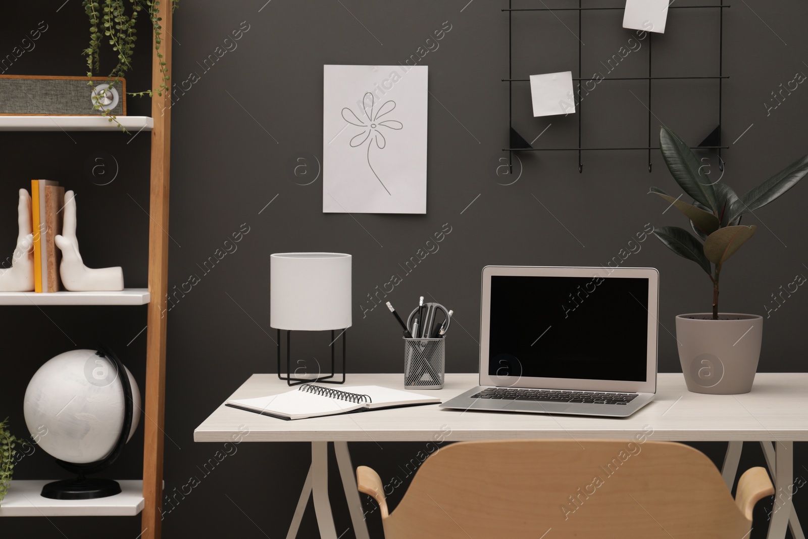 Photo of Cozy workplace with laptop and stationery on desk at home
