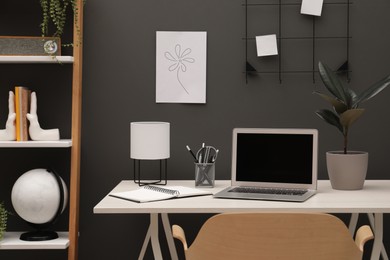 Cozy workplace with laptop and stationery on desk at home