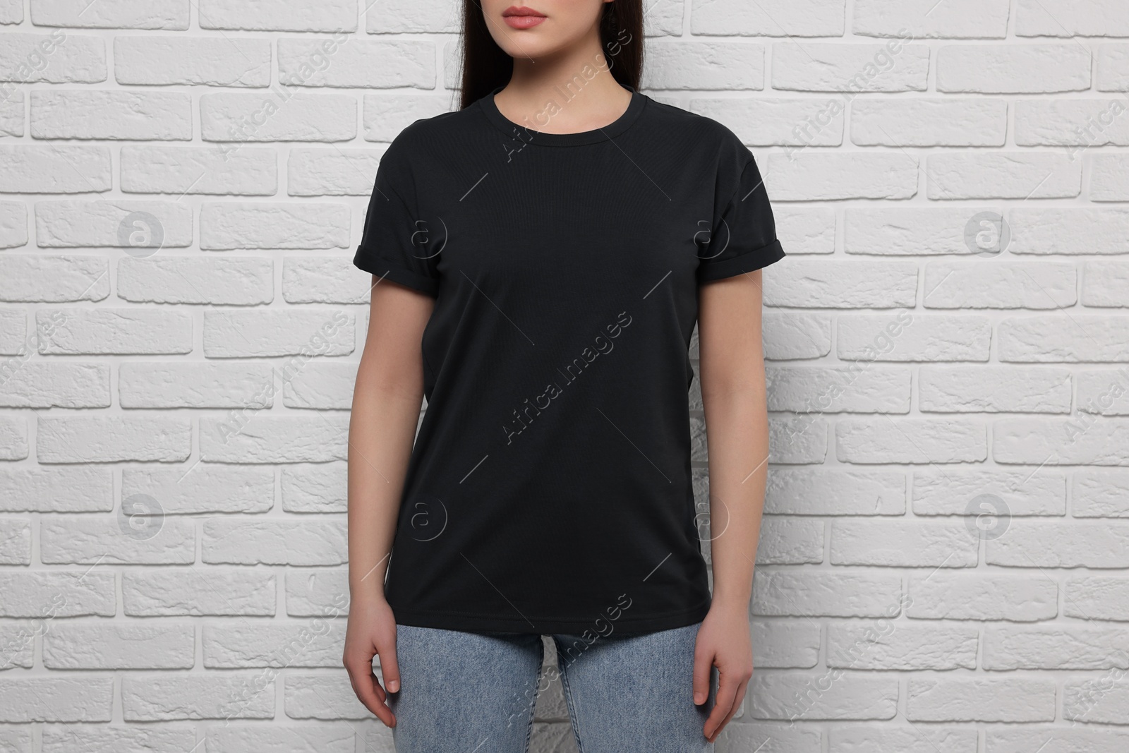 Photo of Woman wearing stylish black T-shirt near white brick wall, closeup