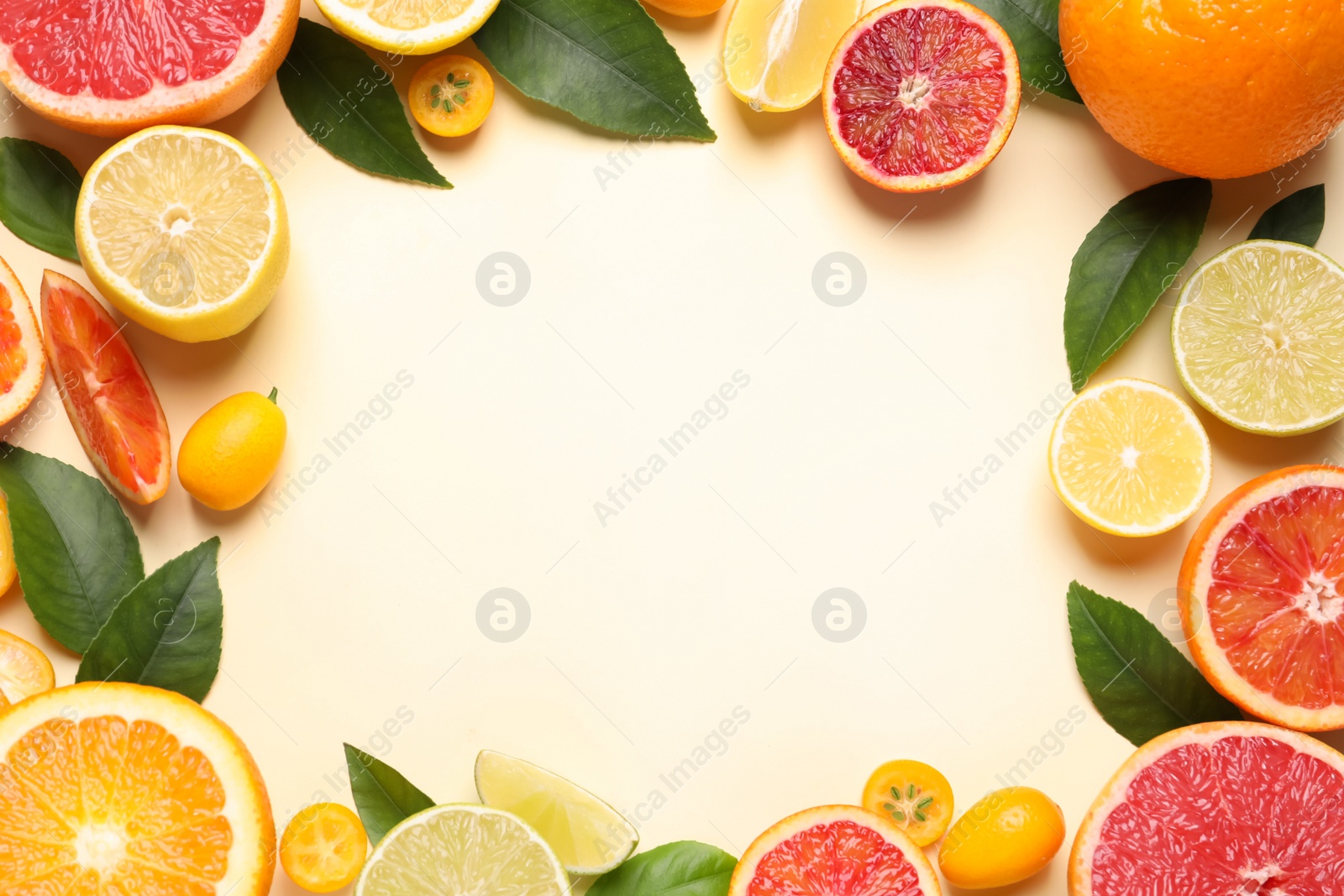 Photo of Frame of fresh juicy citrus fruits with green leaves on beige background, flat lay. Space for text