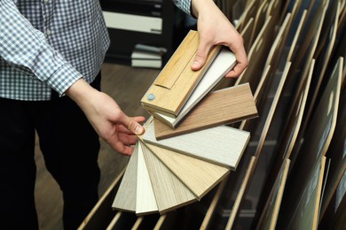 Photo of Man with samples of wooden flooring in shop, closeup