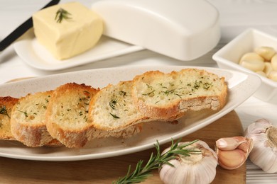 Photo of Tasty baguette with garlic and dill served on white table
