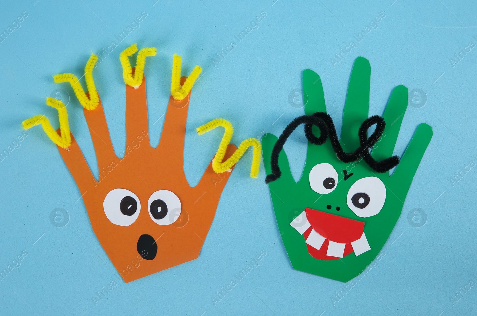 Photo of Funny hand shaped monsters on light blue background, flat lay. Halloween decoration