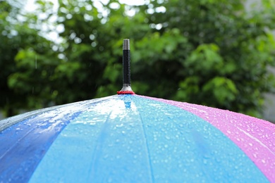 Photo of Colorful umbrella outdoors on rainy day, closeup