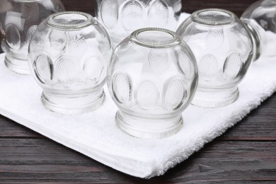 Photo of Glass cups and towel on wooden table, closeup. Cupping therapy