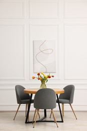 Photo of Stylish dining room interior with comfortable furniture and beautiful tulips