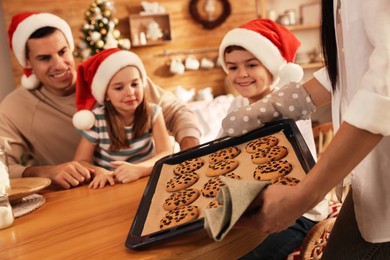 Photo of Happy mother giving her family freshly baked delicious Christmas cookies at home, closeup