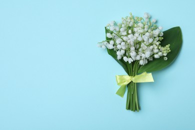 Photo of Beautiful lily of the valley flowers on light blue background, top view. Space for text