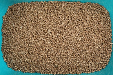 Photo of Wood pellet cat litter in light blue plastic container, top view