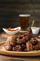 Delicious chicken wings served with beer on wooden table