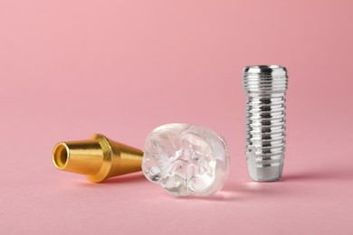 Photo of Parts of dental implant on pink background, closeup
