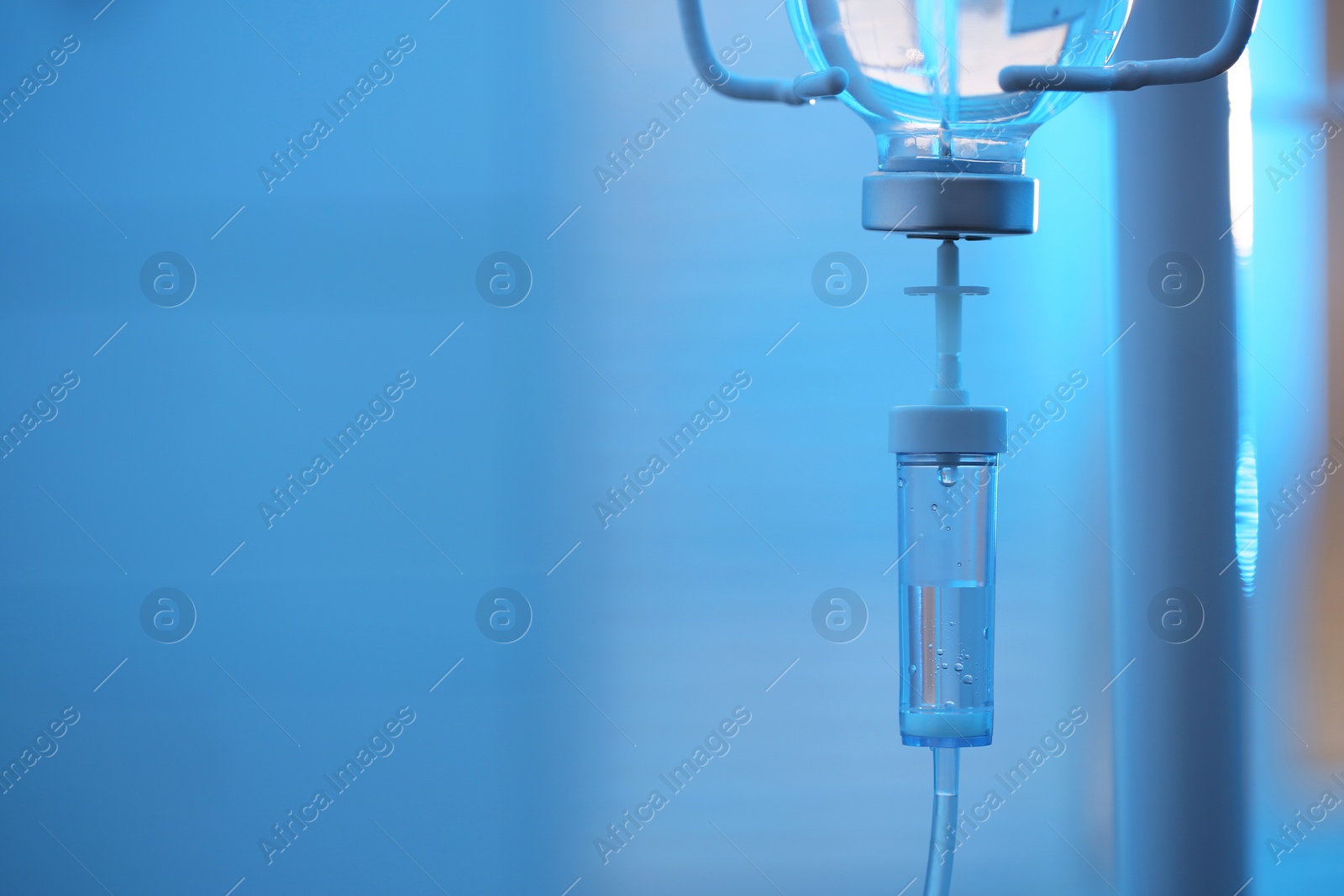 Photo of IV drip against blurred light blue background, space for text