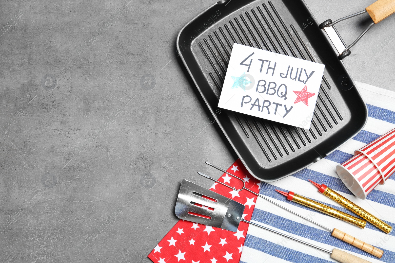 Photo of Flat lay composition with barbecue tools, grill pan and card on color background, space for text. USA Independence Day