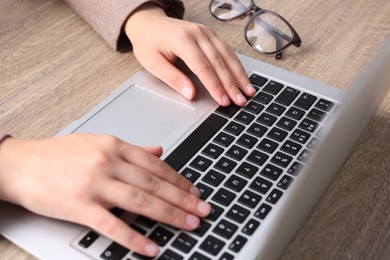 Woman working on laptop at wooden table, closeup