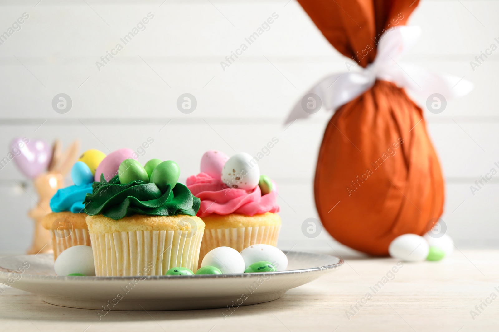 Photo of Tasty cupcakes with Easter decor on wooden table, space for text