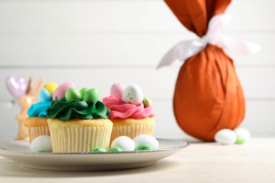 Photo of Tasty cupcakes with Easter decor on wooden table, space for text