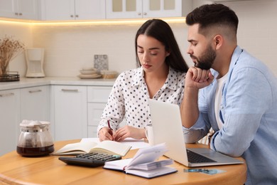 Photo of Young couple discussing family budget in kitchen