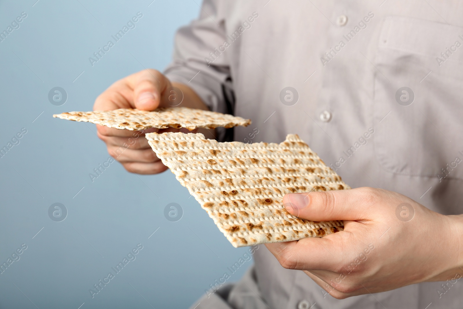 Photo of Man with Matzo on grey background, closeup. Pesach (Passover) celebration