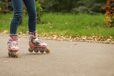 Photo of Cute girl roller skating in autumn park, focus on legs