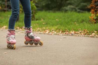 Cute girl roller skating in autumn park, focus on legs