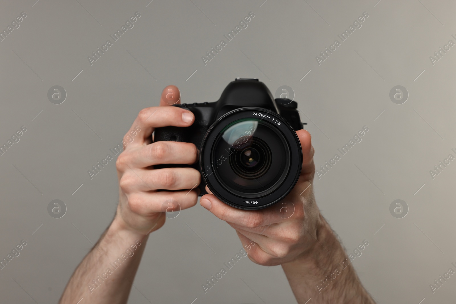 Photo of Photographer holding camera on grey background, closeup