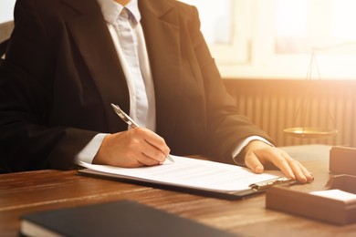 Image of Lawyer working with document at wooden table in office, closeup