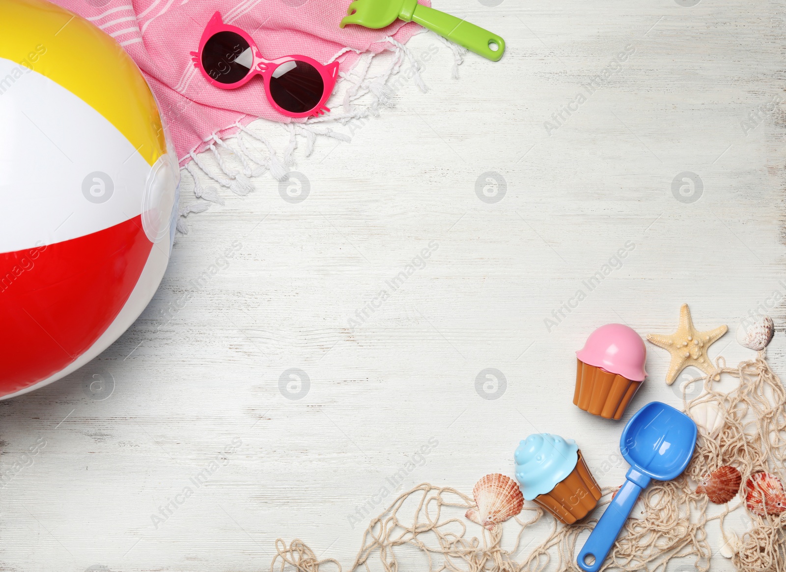 Photo of Flat lay composition with beach toys on white wooden background. Space for text