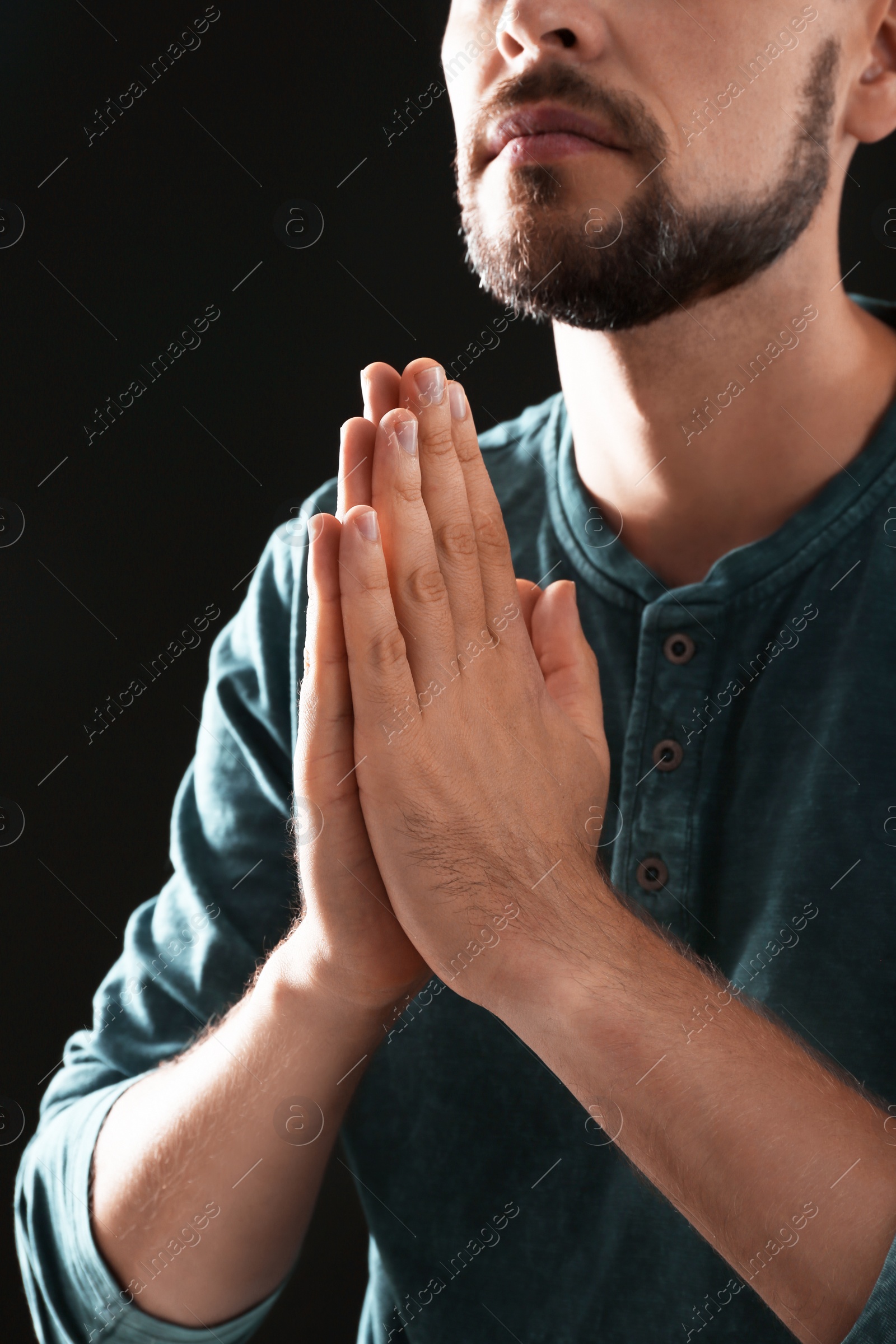 Photo of Man with hands clasped together for prayer on black background