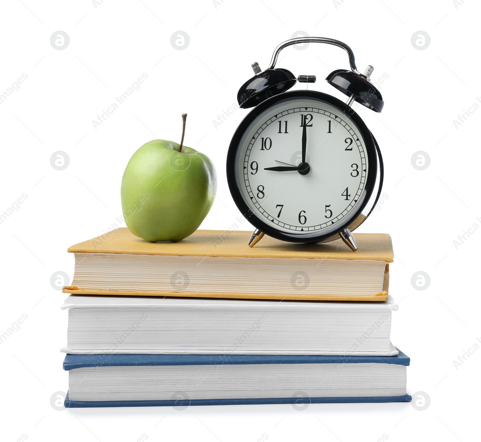 Photo of Black alarm clock, different books and apple on white background. School time