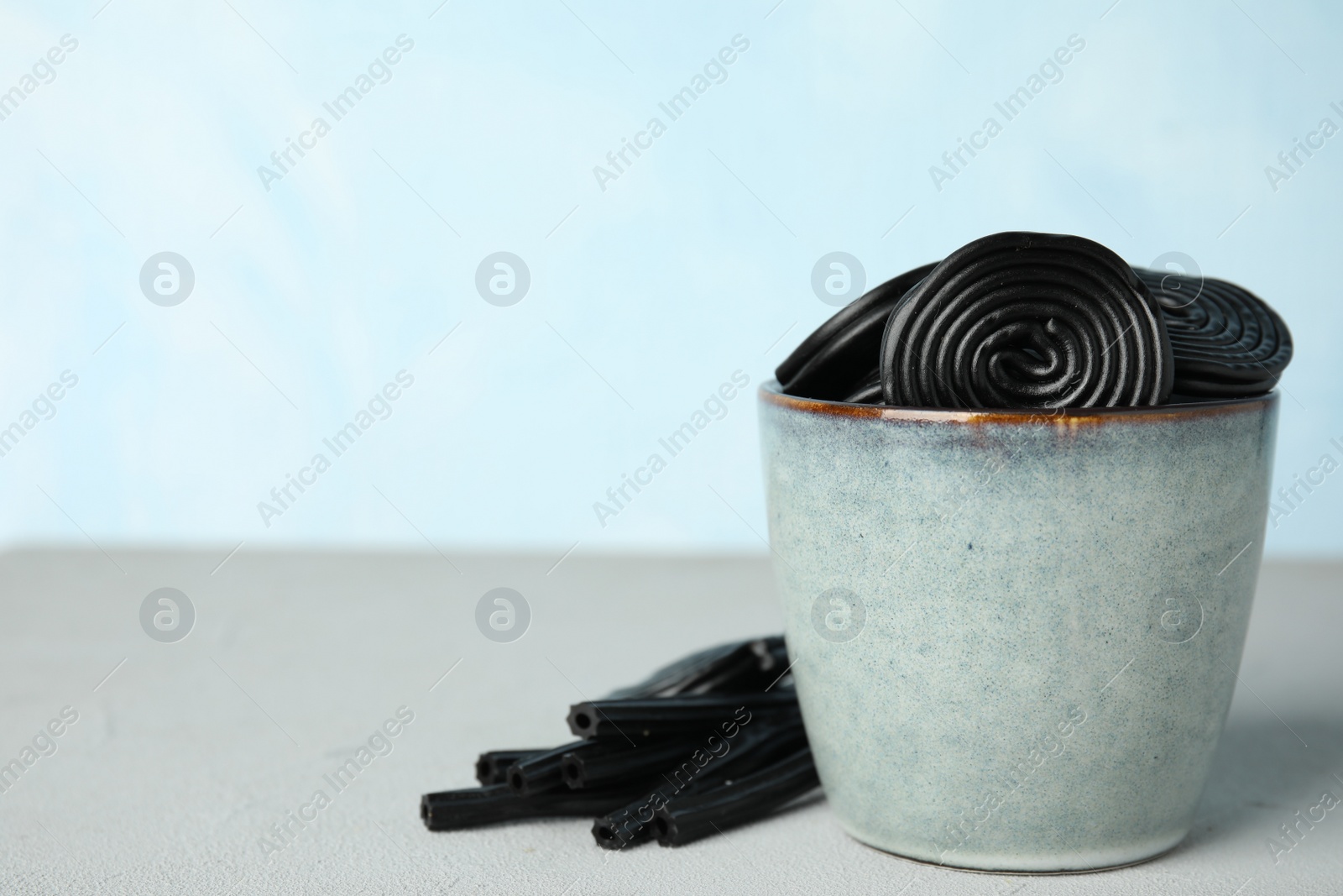 Photo of Tasty black liquorice candies on grey table. Space for text