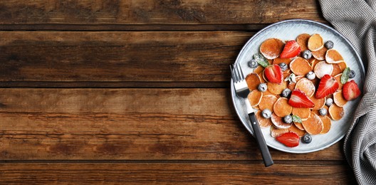 Photo of Cereal pancakes with berries served on wooden table, flat lay. Space for text