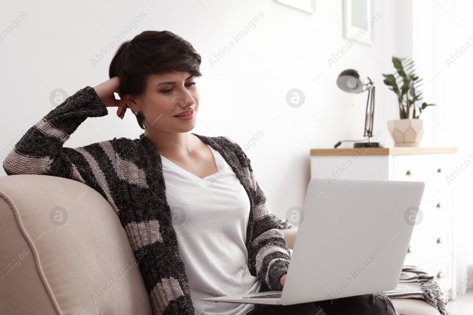 Photo of Young woman working with laptop at home