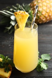 Delicious fresh pineapple juice on black wooden table, closeup