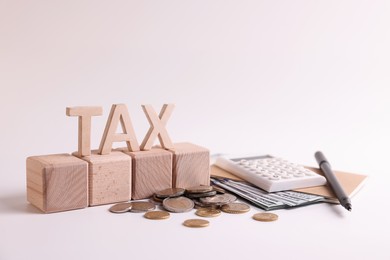 Photo of Word Tax, number 2024 made of wooden cubes, calculator, coins and banknotes on white background
