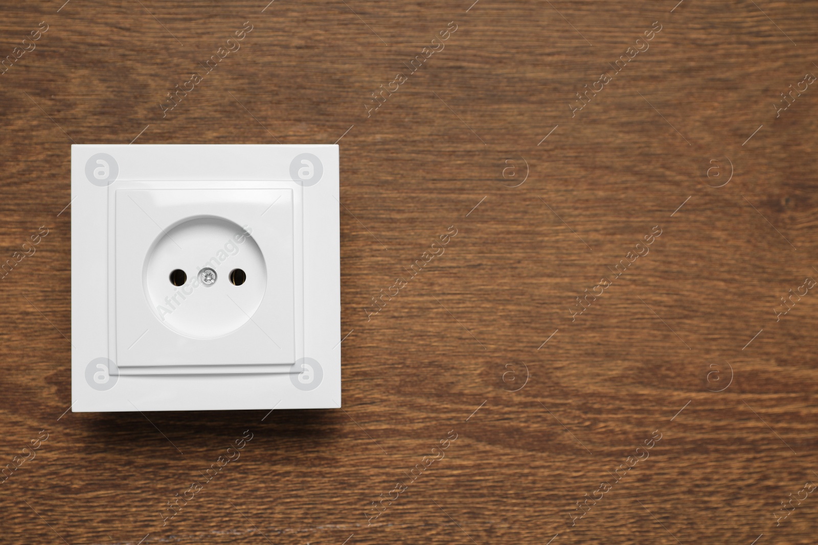 Photo of Modern plastic power socket on wooden table, top view. Space for text