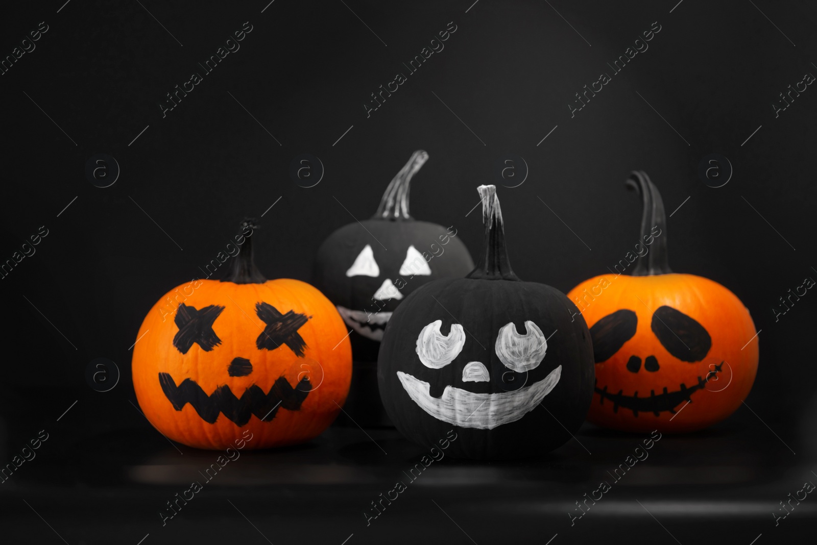 Photo of Halloween celebration. Pumpkins with drawn faces on table in darkness