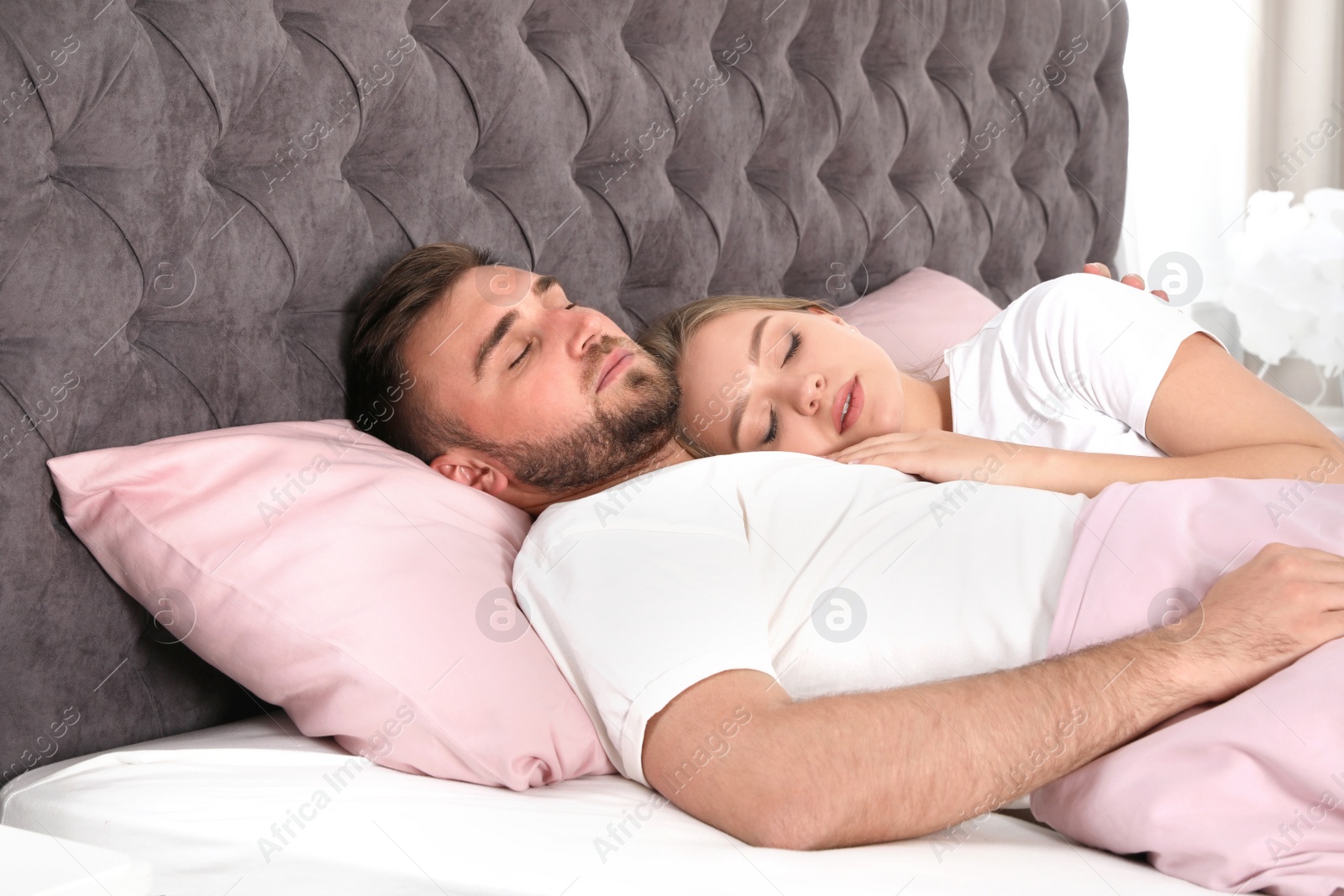 Photo of Young couple sleeping together in bed at home