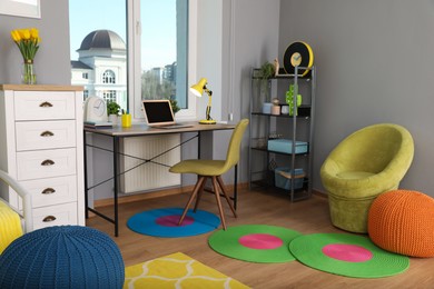 Photo of Comfortable workplace with modern laptop near window in child room. Interior design
