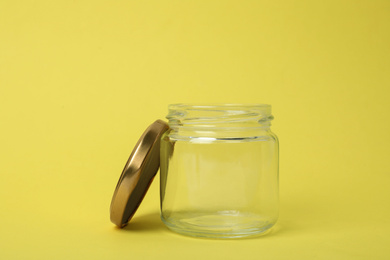 Photo of Open empty glass jar on light yellow background