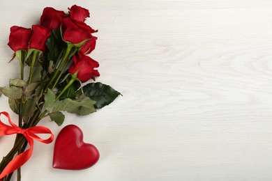 Photo of Beautiful red roses and decorative heart on white wooden background, flat lay with space for text. Valentine's Day celebration